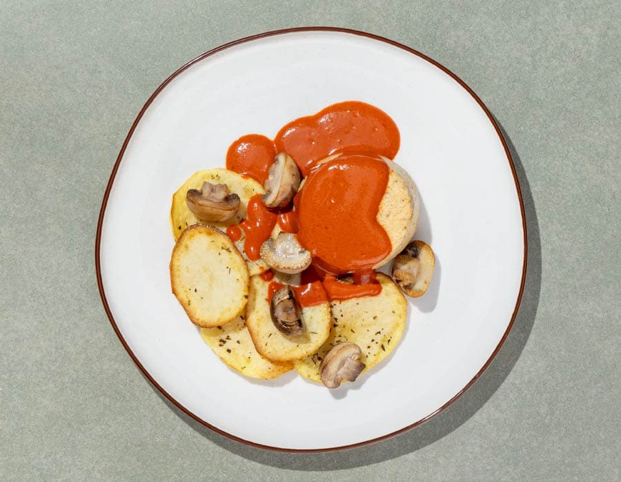 Pastel de merluza, salsa de piquillos y sidra, patatas y champiñones